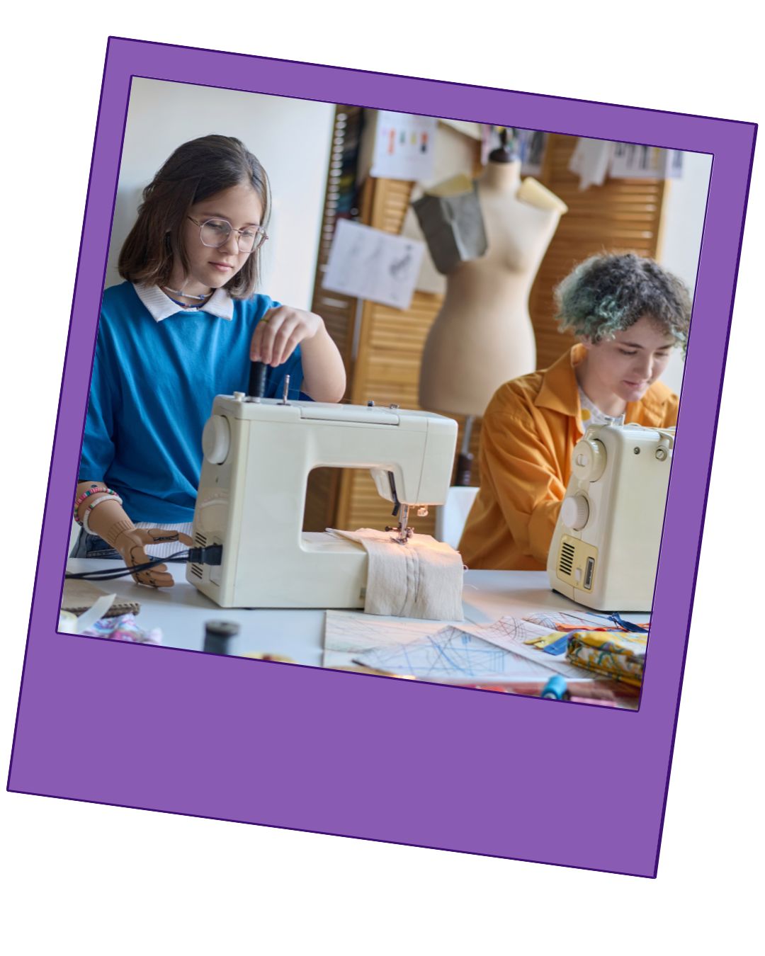 Two teenage girls making crafts using sewing machines. A light purple border surrounds the photo.